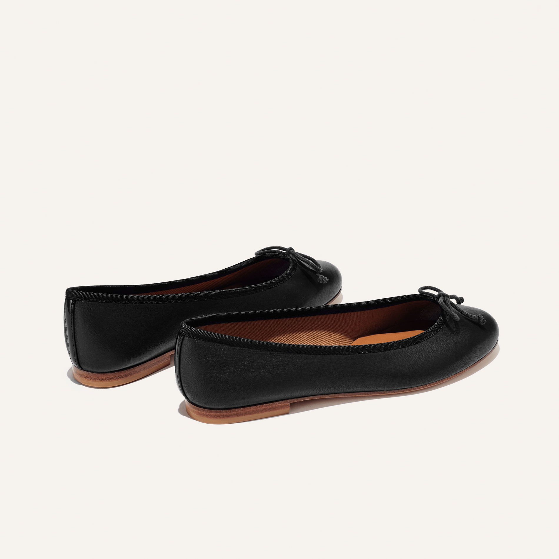The Demi in Black Nappa, a comfortable ballet flat with a rounded toe and adjustable cord bow detail.