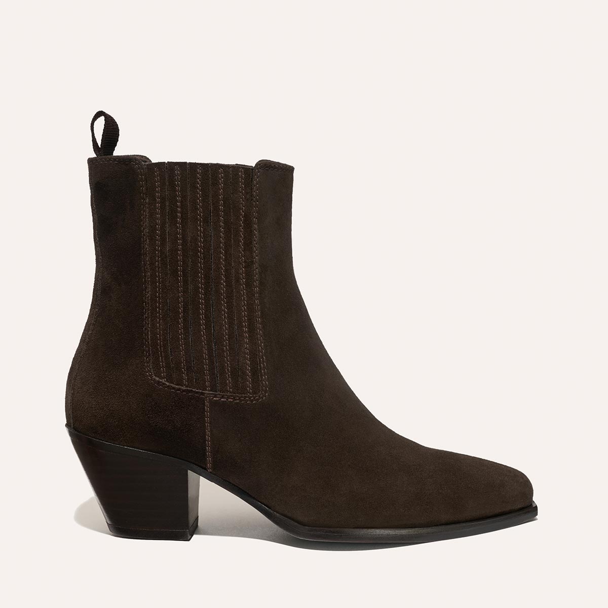 The Agnes Boot - Cocoa Suede by margaux-development is a dark brown suede Western ankle boot with a pointed toe, side stitching, squared welt, back pull tab, and medium block heel, shown in profile against a light background.