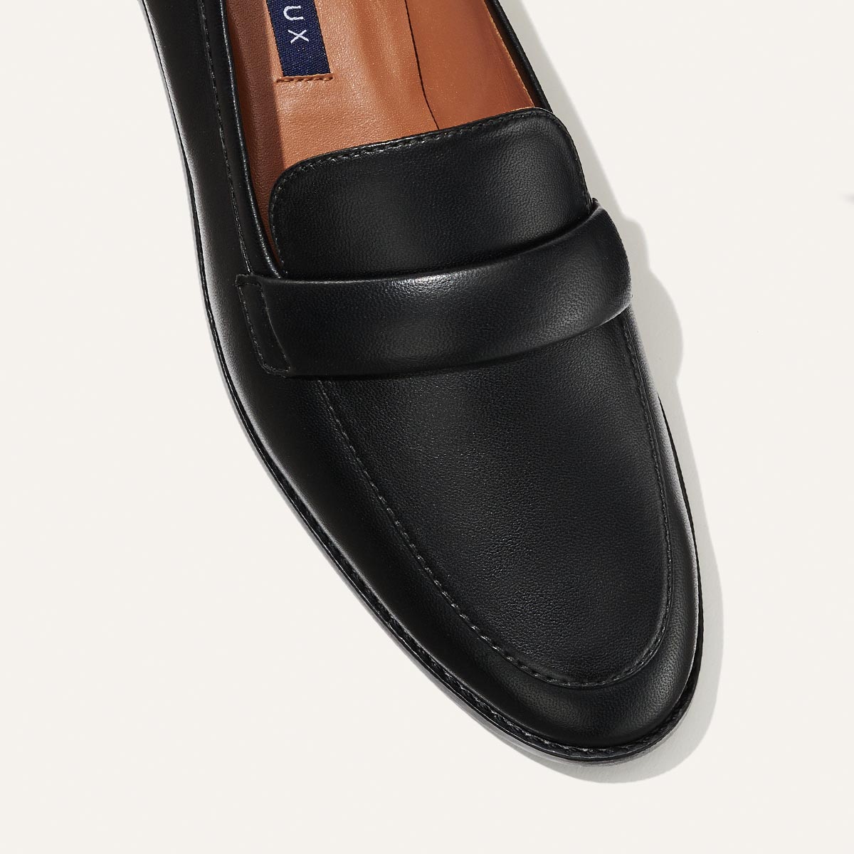 The Andie Loafer in Black Nappa, featuring a sleek structured design made from smooth Italian nappa leather with a minimalistic padded keeper detail.