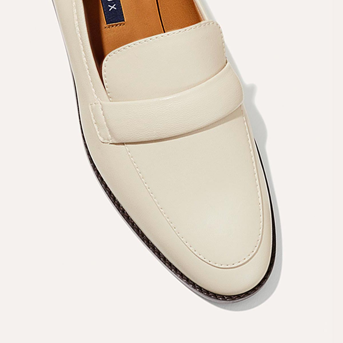 The Andie Loafer in Ecru Nappa, featuring a sleek structured design made from smooth Italian nappa leather with a minimalistic padded keeper detail.