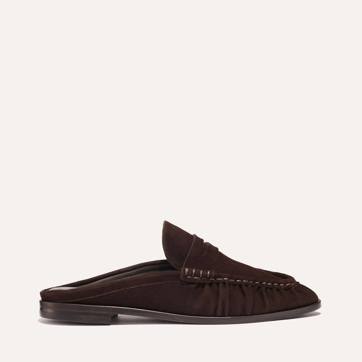 The Astor Loafer Mule in Espresso Suede by margaux-development is a dark brown suede slip-on with visible stitching and a low heel, displayed in side profile against a plain light background.