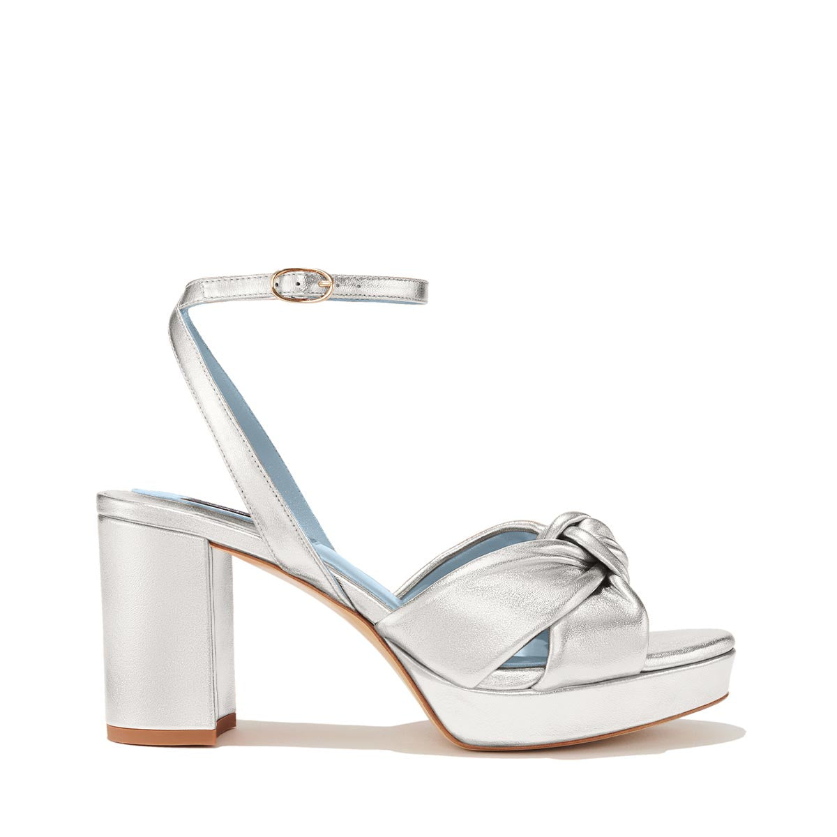 The Carmine Platform by Margaux is a silver high-heeled sandal featuring a thick block heel, platform sole, ankle strap with buckle, and knotted front straps.