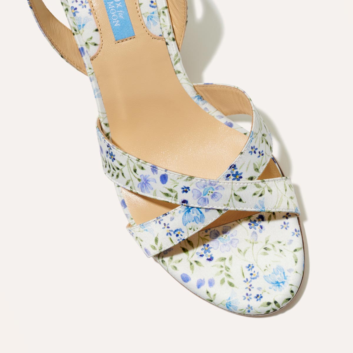 A top view of The City Sandal - Ivory Floral Satin by margaux-development shows its blue and green floral crisscross straps and cushioned insole for comfort.
