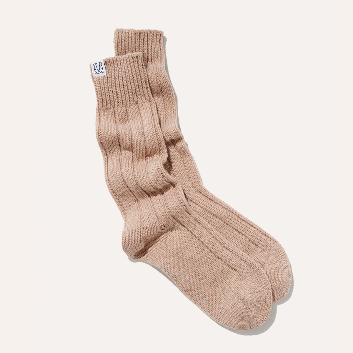 The Cozy Sock by Margaux in Oatmeal, crafted from a soft wool-cashmere blend, features ribbed crew styling and a subtle white tag at the upper edge, shown against a plain light background.