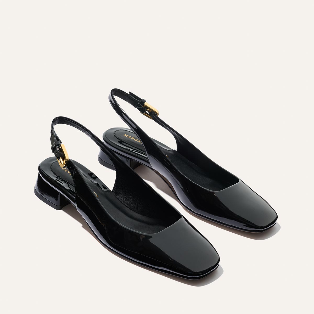 The Darcy Slingback - Black Patent by Margaux features shiny black patent leather, low square heels, square toes, and gold buckle accents on adjustable slingback straps—ideal for elevating your warm-weather style.