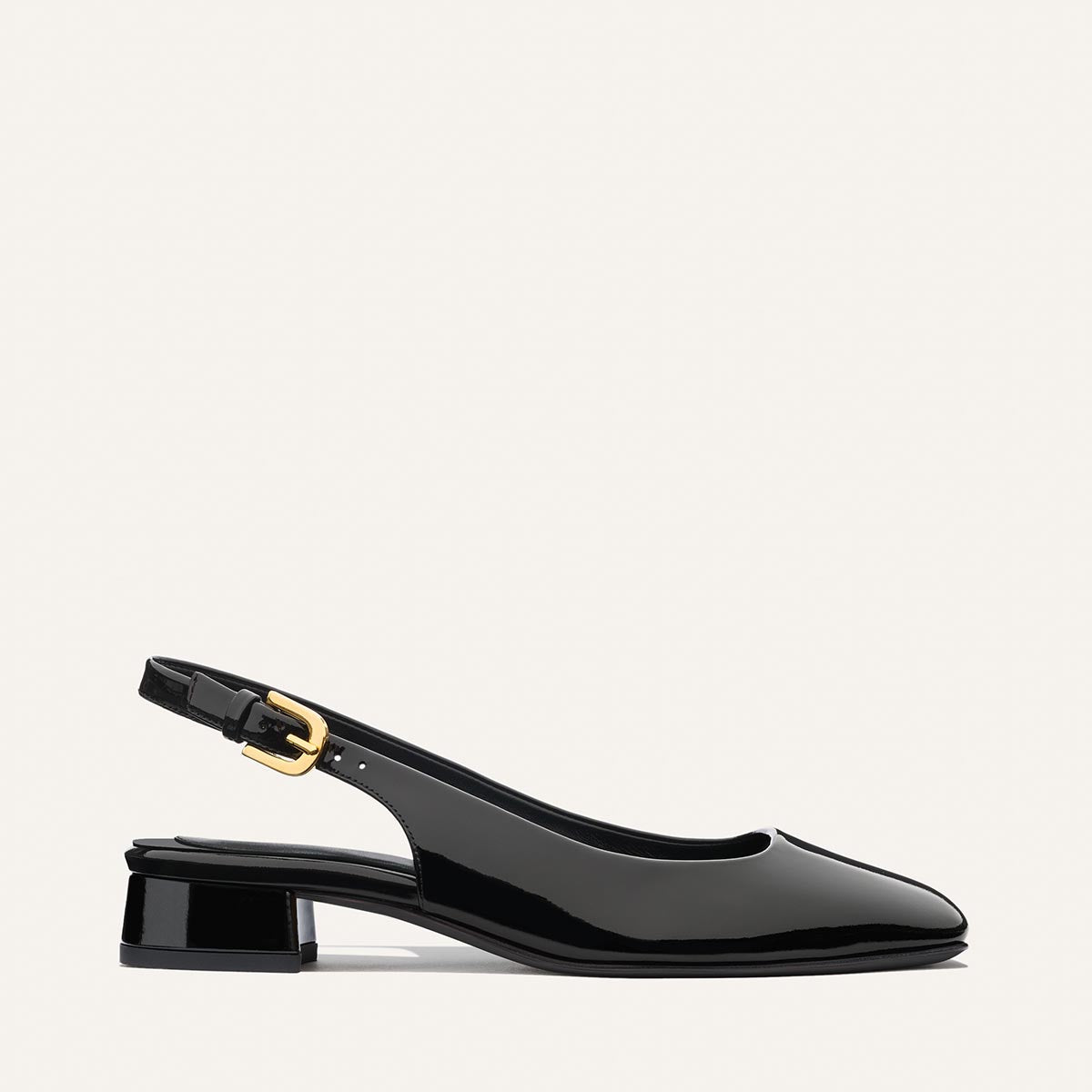 The Darcy Slingback by Margaux in black patent features a low block heel, gold buckle, adjustable slingback, and almond toe—ideal for warm-weather style and shown against a plain light background.