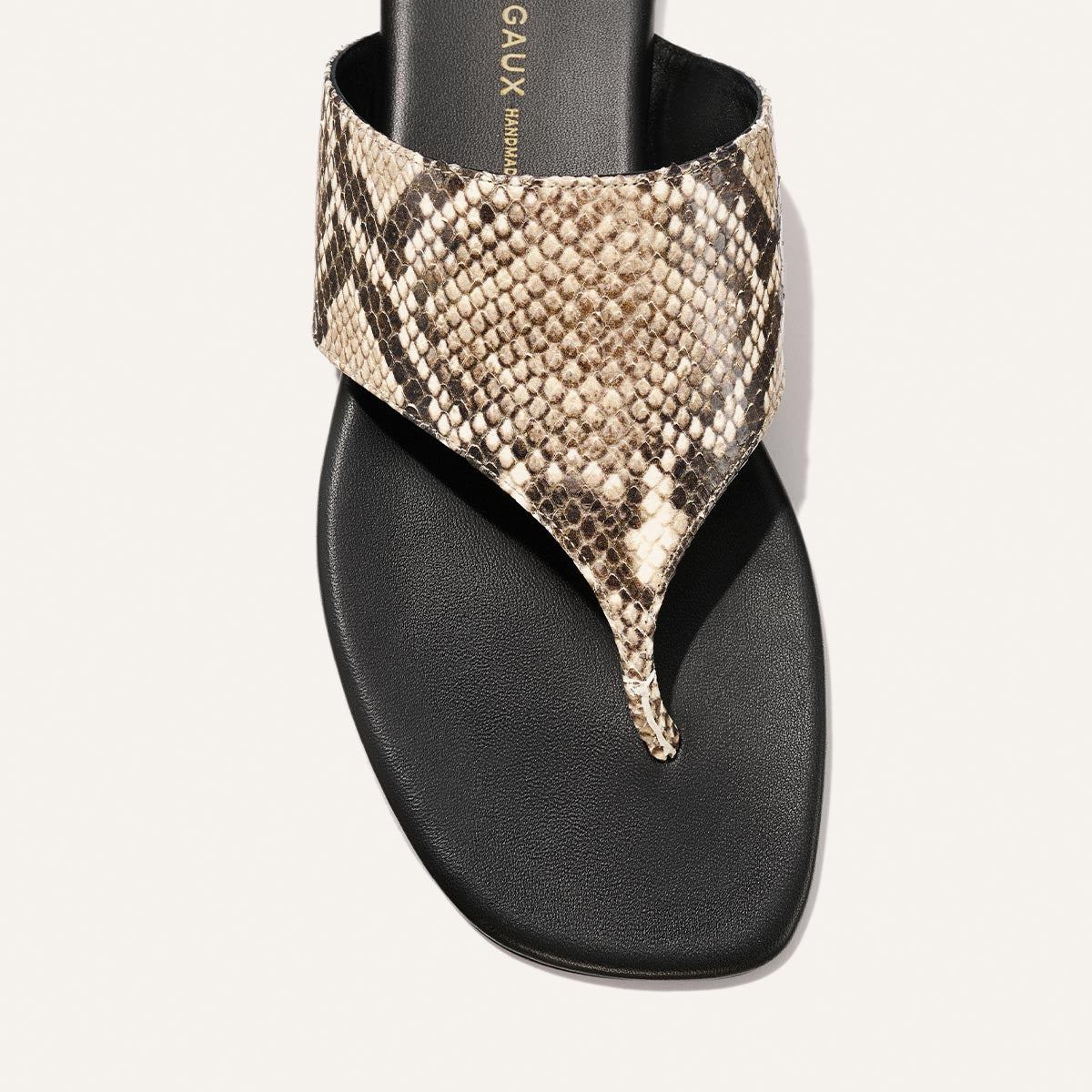 Black sandal with snake print strap on a white background