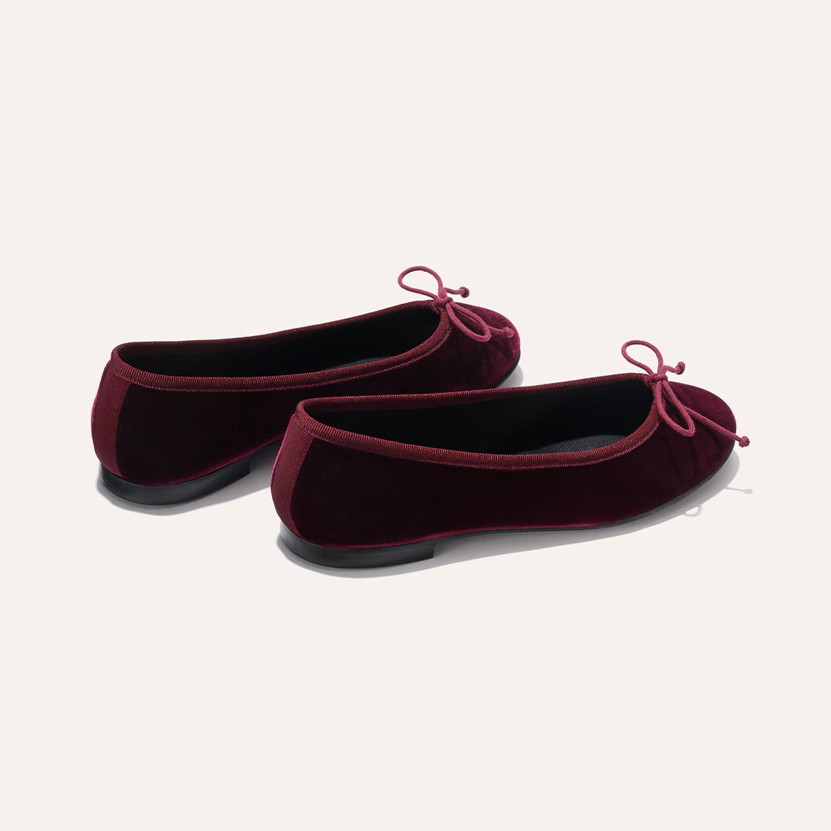 The Demi - Burgundy Velvet by margaux-development: a pair of burgundy velvet ballet flats with small matching bows, shown from the back and side on a plain light background.