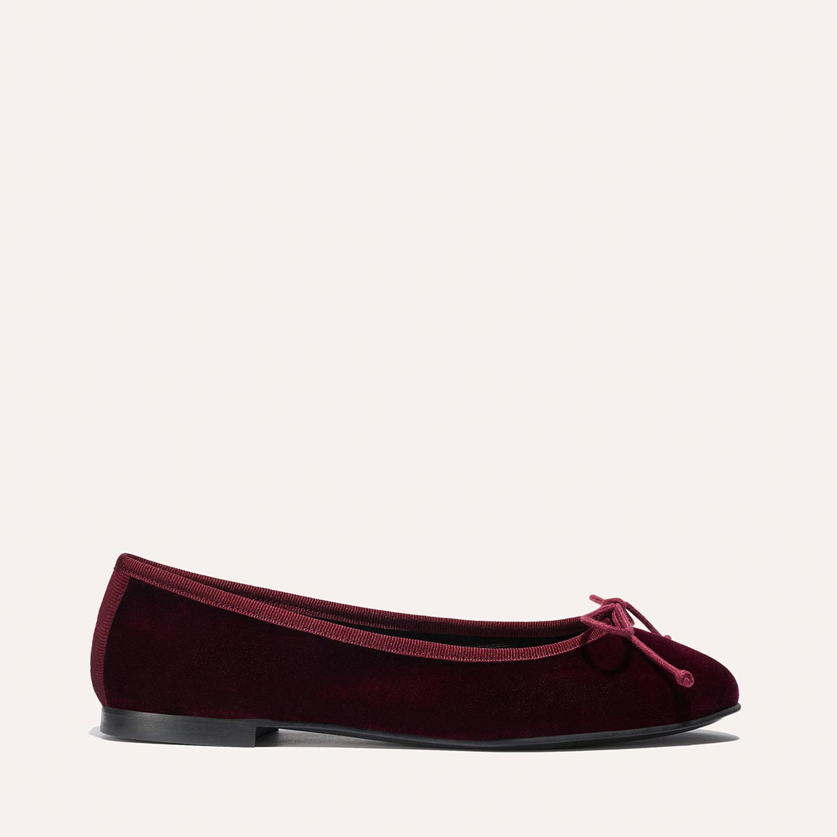 The Demi - Burgundy Velvet by margaux-development: a single burgundy velvet ballet flat with a rounded toe, matching trim, and a small bow on the front, set against a plain light background.