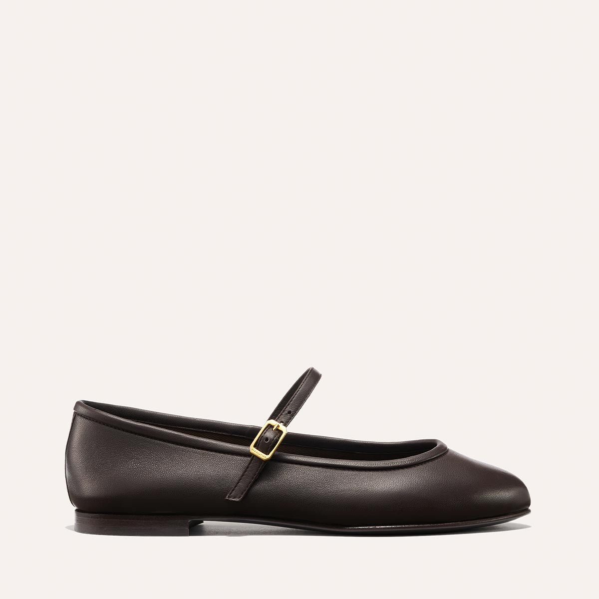 The Demi Jane - Espresso Nappa by margaux-development is a dark brown leather Mary Jane flat with a thin strap and gold buckle, shown in profile against a light background, exuding elegant femininity.