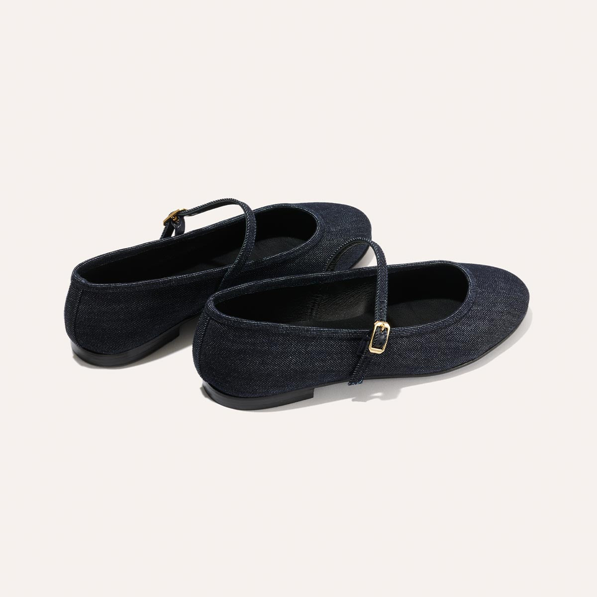 The Demi Jane - Indigo Denim by margaux-development: dark blue denim Mary Jane flats with black soles and gold buckle details on the straps, a perfect blend of elegance and femininity, shown on a light background.