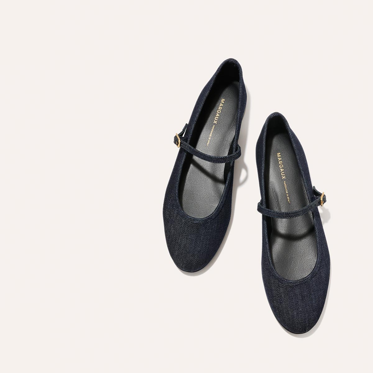 The Demi Jane - Indigo Denim by margaux-development: elegant, indigo denim Mary Jane flats with ankle straps and gold buckles, displayed side by side on a light beige background.