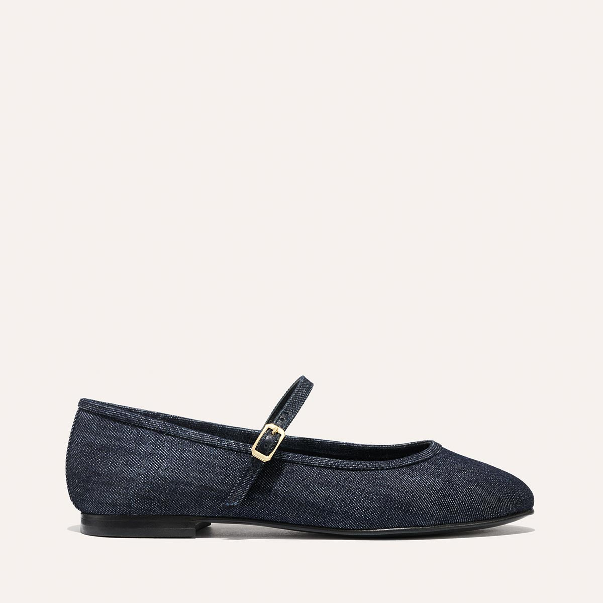 The Demi Jane - Indigo Denim by margaux-development features a dark denim Mary Jane flat with a rounded toe, slim gold-buckled strap, and black soleāan effortlessly elegant feminine touch.