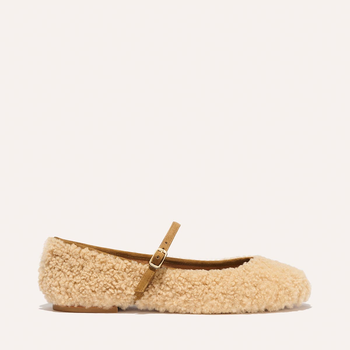 The Demi Jane - Tan Shearling by margaux-development is a beige, fluffy Mary Jane flat featuring shearling-like texture, a thin tan buckle strap, and a flat brown sole for an elegant, feminine look.
