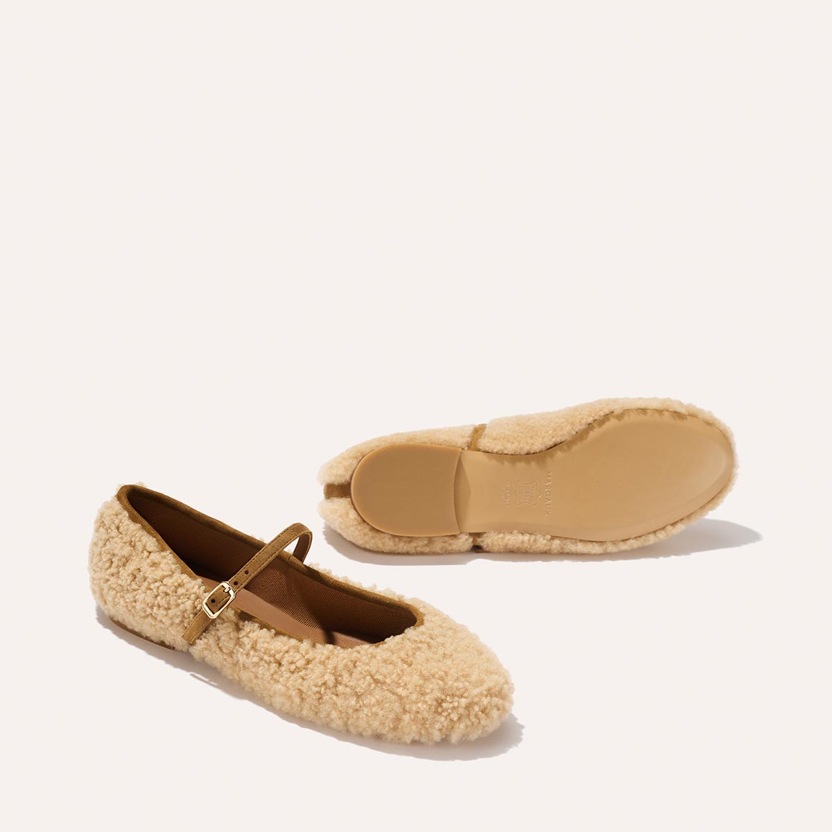 The Demi Jane - Tan Shearling by margaux-development: a pair of beige shearling Mary Jane flats with buckle straps—one upright highlighting the soft texture, the other on its side showing the smooth sole for an elegant, feminine look.