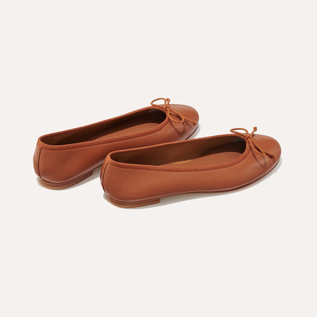 The Demi in Saddle Nappa, a comfortable ballet flat with a rounded toe and adjustable cord bow detail.