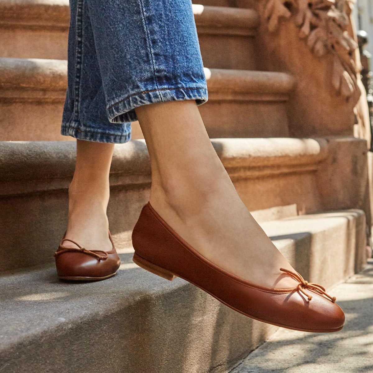 The Demi in Saddle Nappa, a comfortable ballet flat with a rounded toe and adjustable cord bow detail.