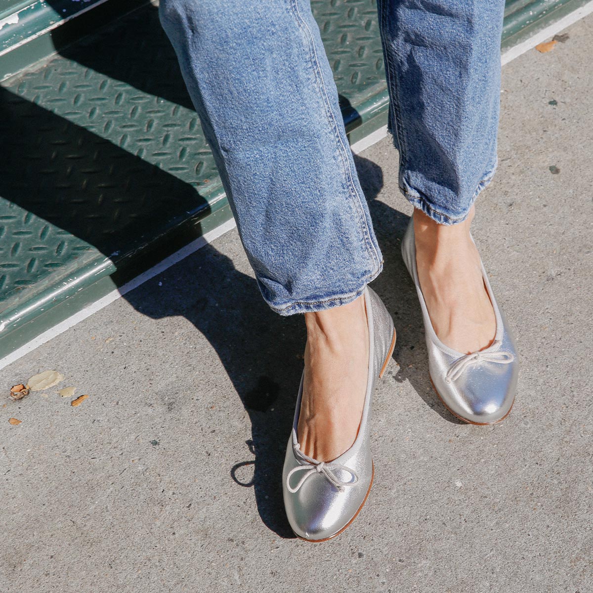 The Demi in metallic Silver Nappa, a comfortable ballet flat with a rounded toe and adjustable cord bow detail.