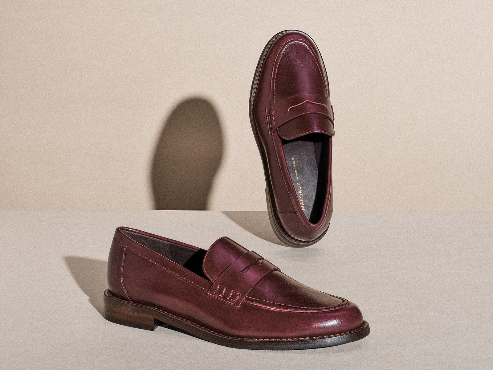 Pair of maroon loafers on a beige background