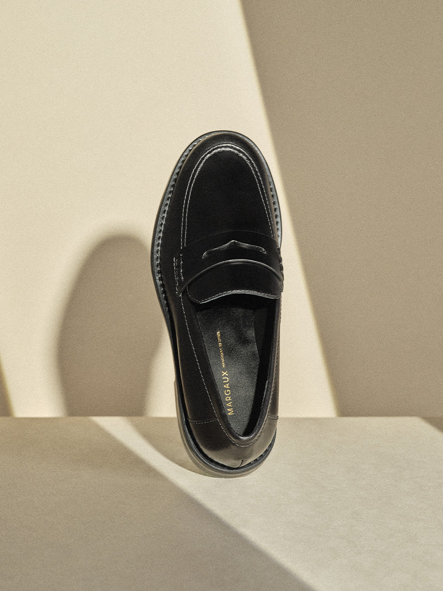 Black loafer shoe on a beige background