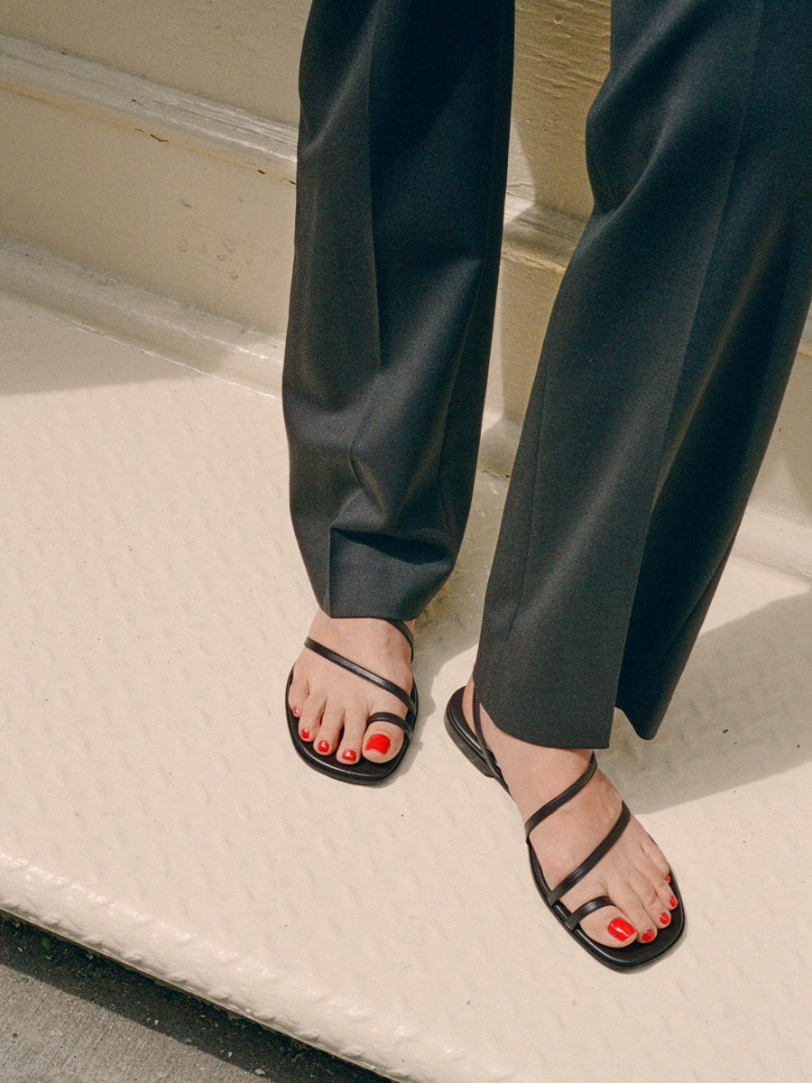 A person wearing black pants and sandals.