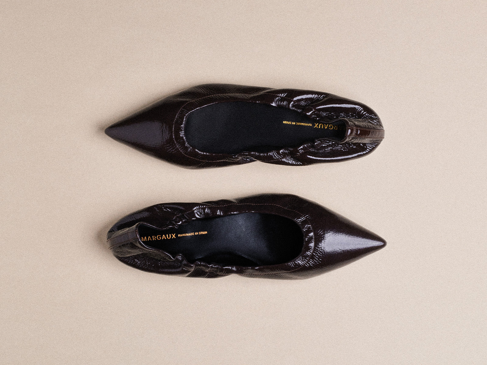 Pair of black pointed toe shoes on a beige background