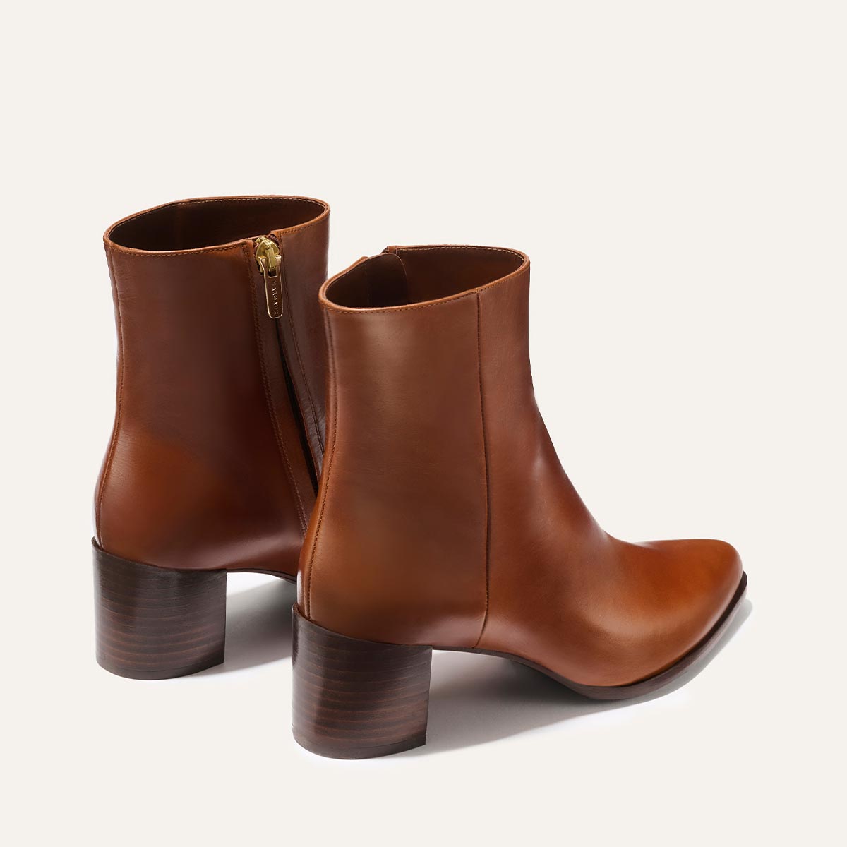 The Downtown Boot - Saddle Calf by Margaux features brown leather, stacked block heels, rounded toes, and side zippers, displayed on a light background.