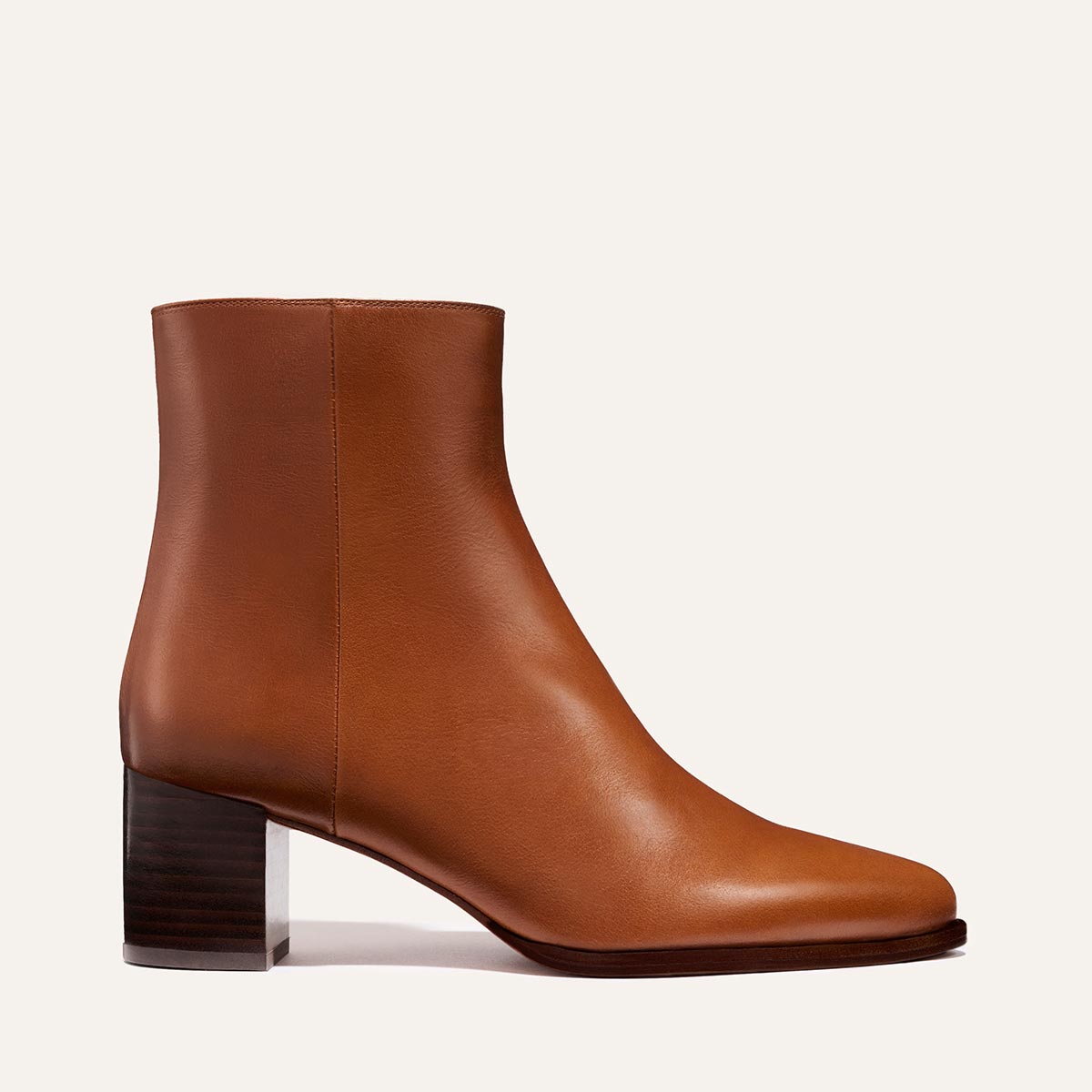 The Downtown Boot - Saddle Calf by Margaux is a tan leather Western ankle boot featuring a rounded toe and a chunky, mid-height stacked leather heel, displayed in profile against a plain light background.