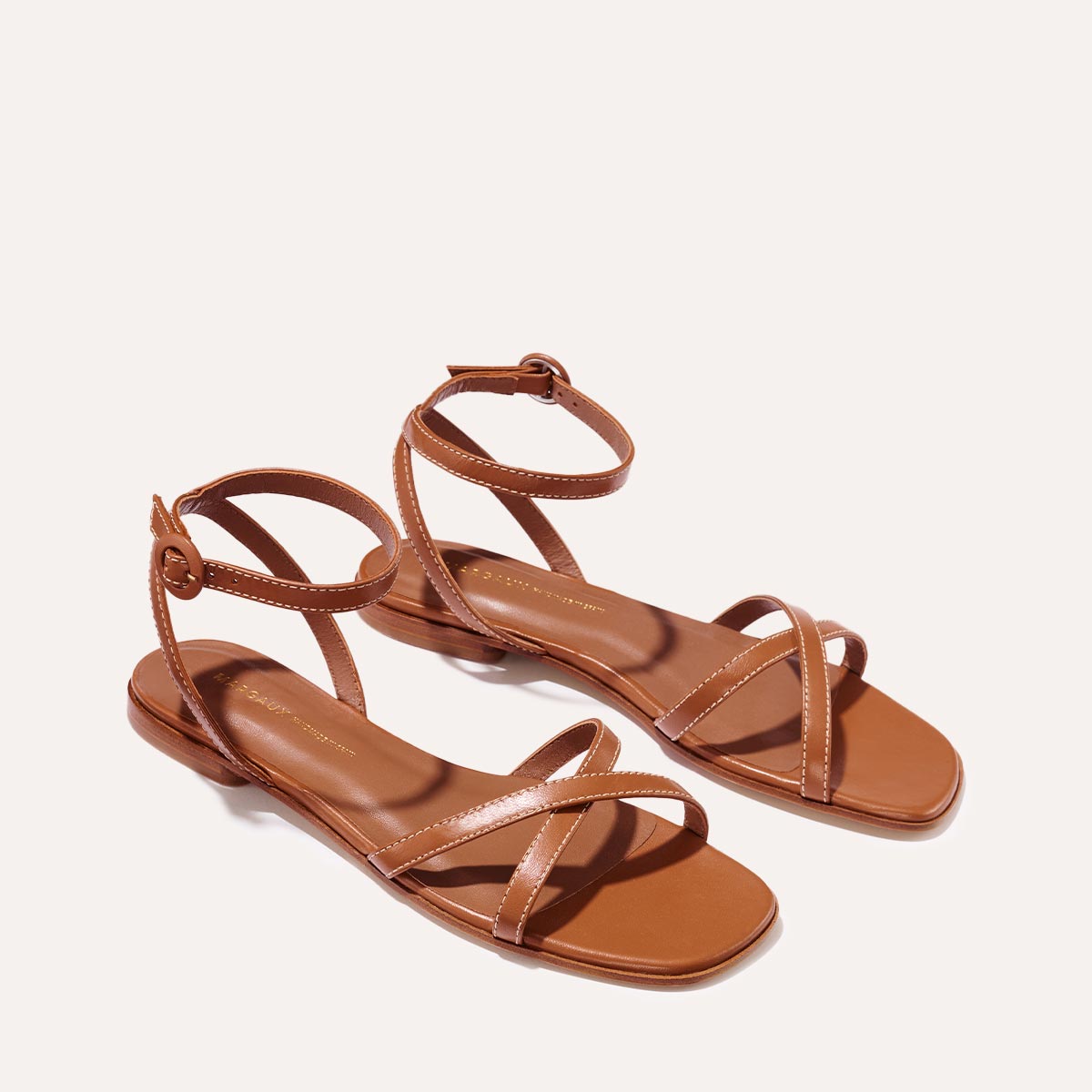 The Flat Sandal in saddle brown nappa, a minimal sandal featuring thin, flattering straps with a subtly square toe.