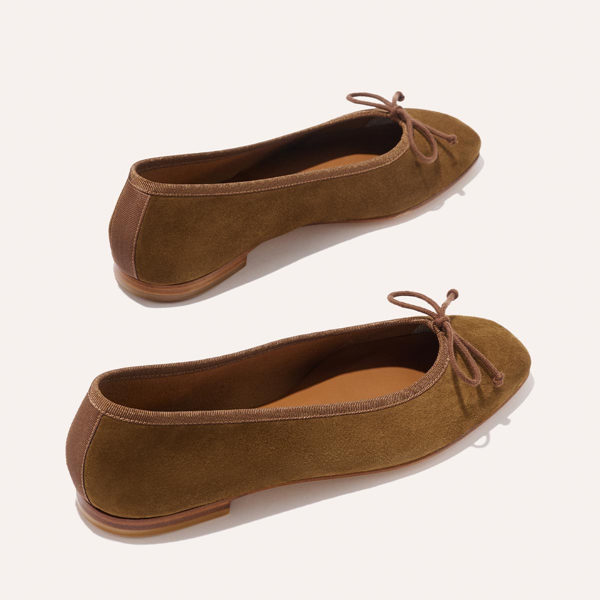 The Fonteyn - Cedar Suede by Margaux: brown suede ballet flats with rounded toes, delicate front bows, and flat wooden soles, displayed on a light background.