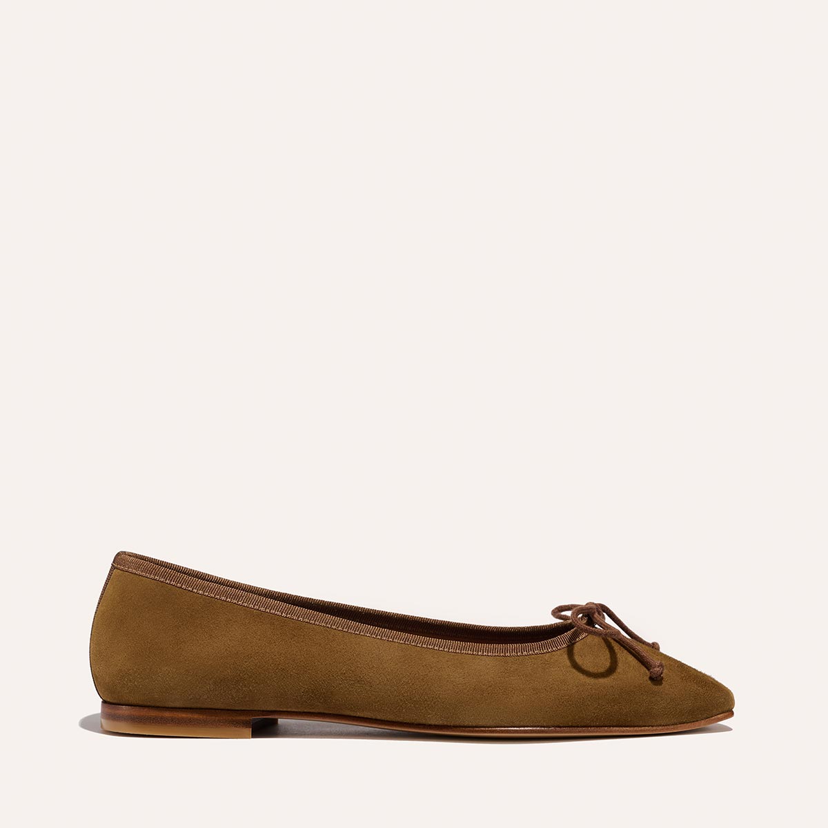 The Fonteyn - Cedar Suede by Margaux is a brown suede ballet flat with a small bow on the rounded toe, low heel, and simple profile, shown from the side against a plain light background.