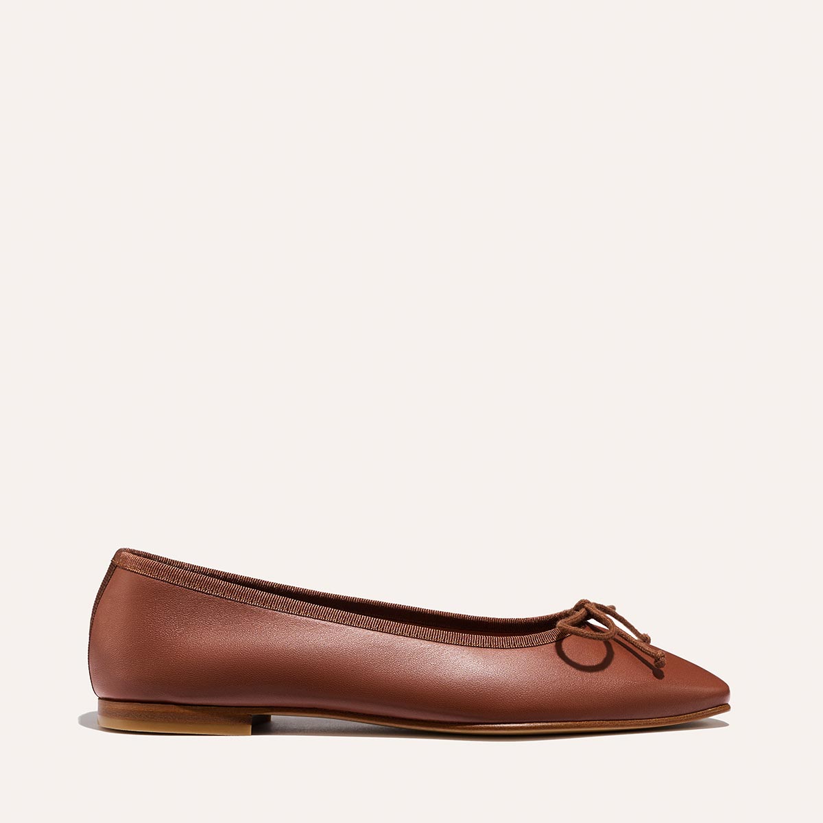 The Fonteyn - Cognac Nappa by Margaux: a brown leather ballet flat with a small bow on the rounded toe, shown in side view against a plain light background.