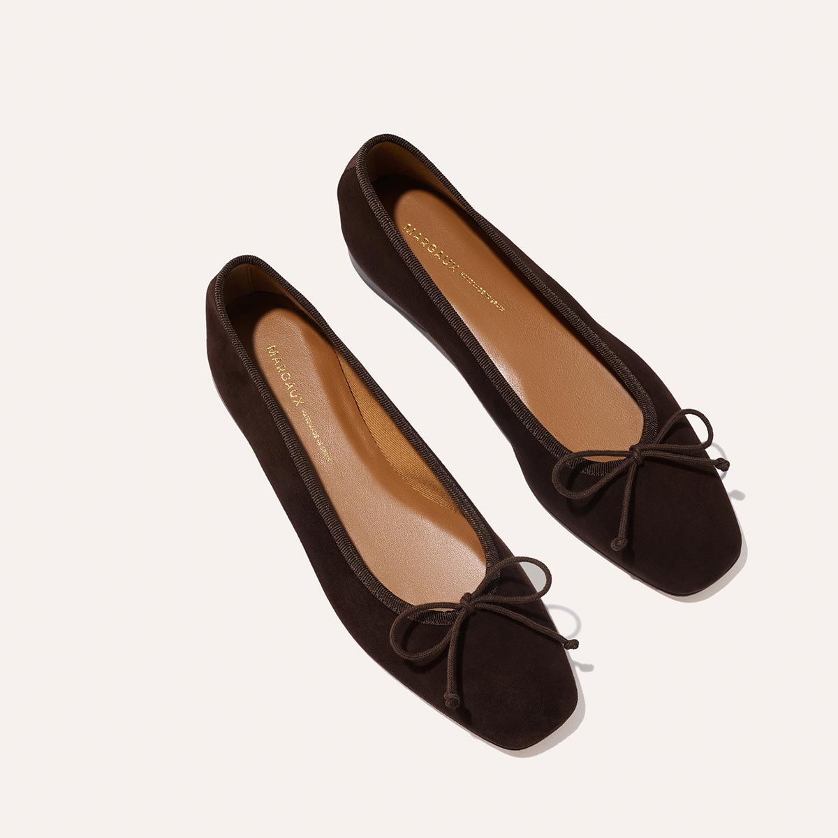 The Fonteyn - Espresso Suede by Margaux: handcrafted dark brown suede ballet flats with square toes and bow accents, displayed on a light background.