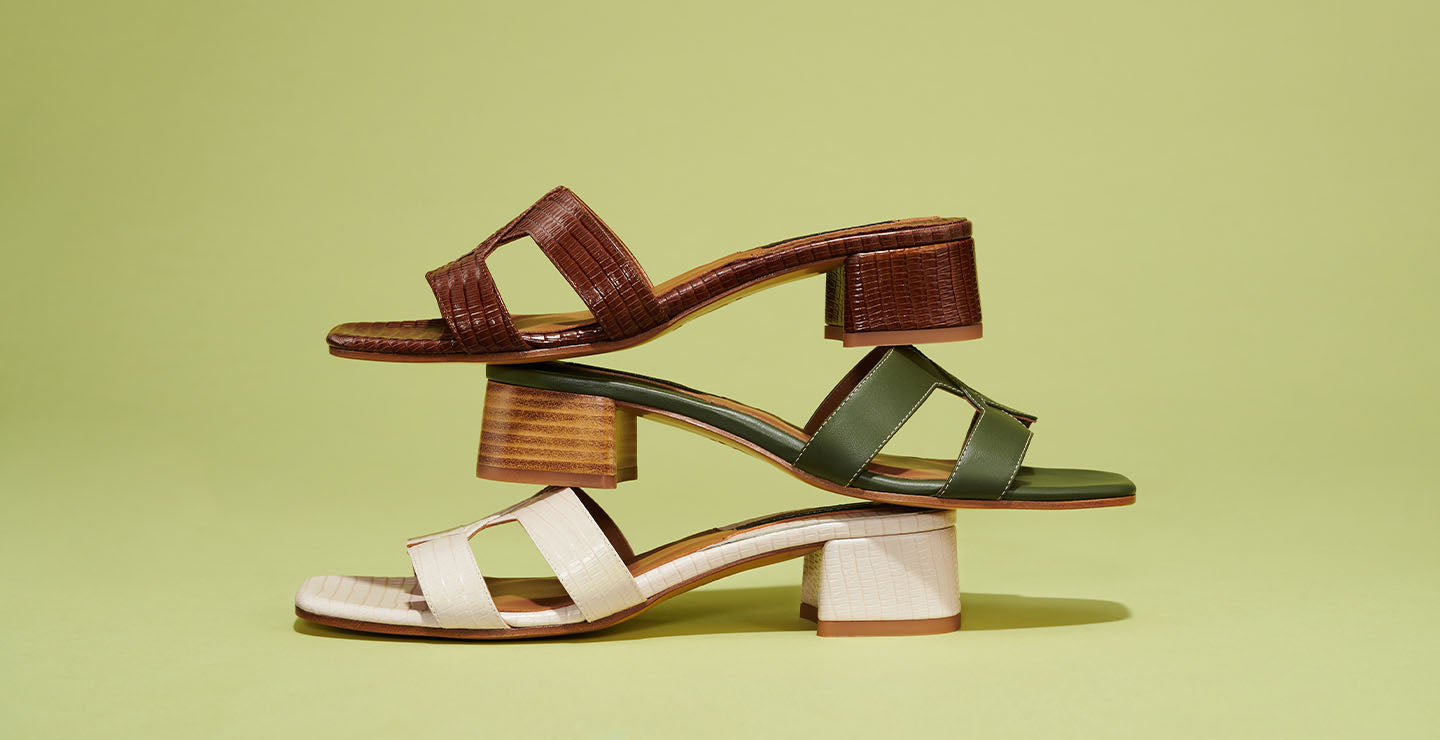 Three pairs of heeled sandals in brown, green, and off-white, stacked horizontally on top of each other against a light green background.