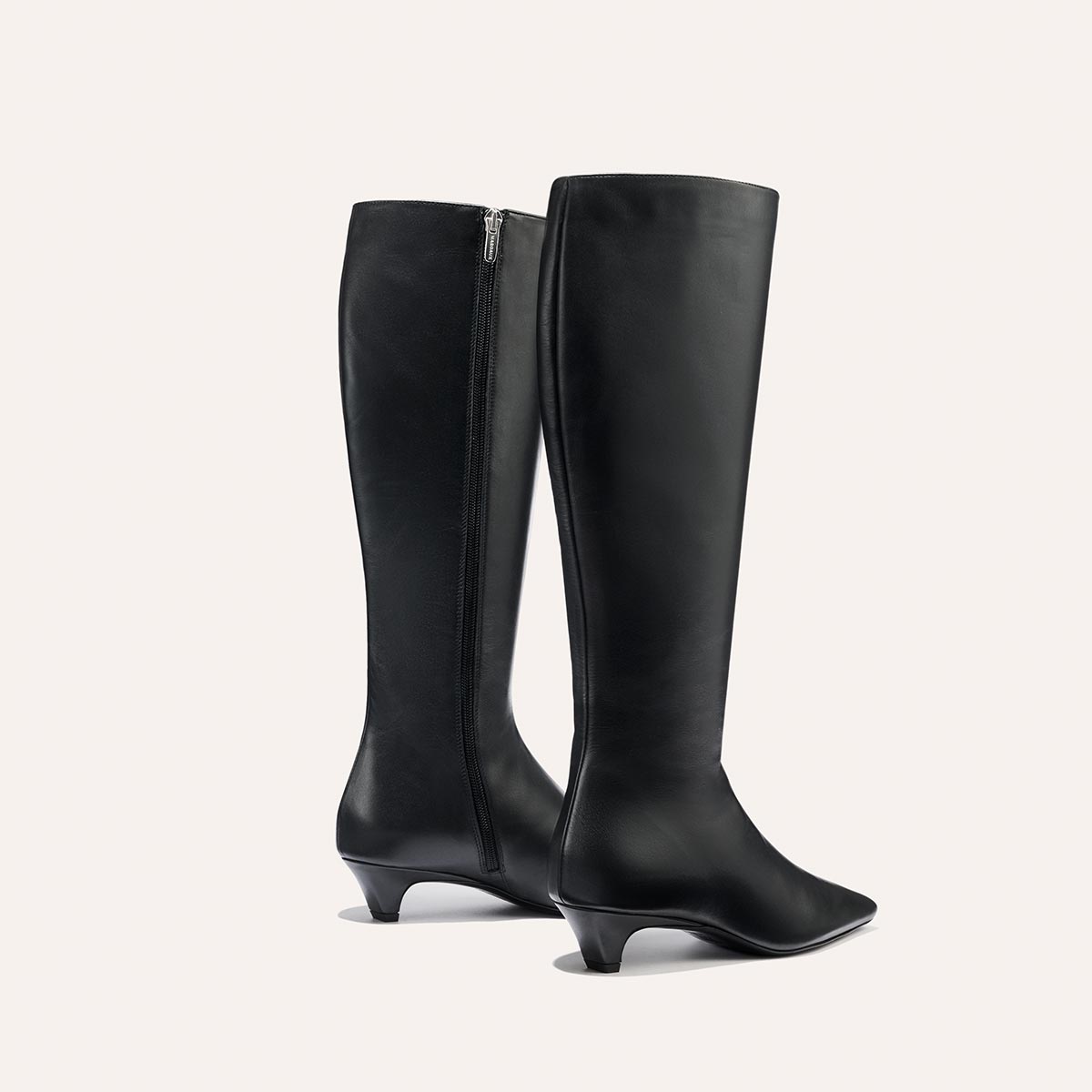 The Imogen - Black Calf by Margaux: sleek black knee-high leather boots featuring a side zipper and low, curved heels, showcased against a plain light background.