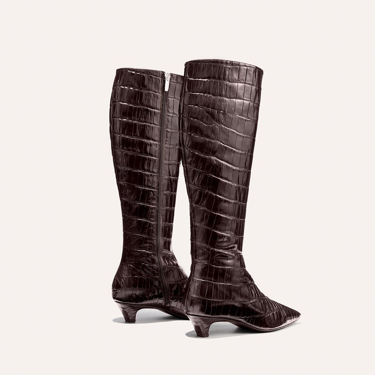 The Imogen - Espresso Croc Embossed boots by Margaux feature tall, dark brown crocodile-embossed leather, low heels, and pointed toes. Displayed on a plain light background, one boot is slightly turned to reveal the side zipper.