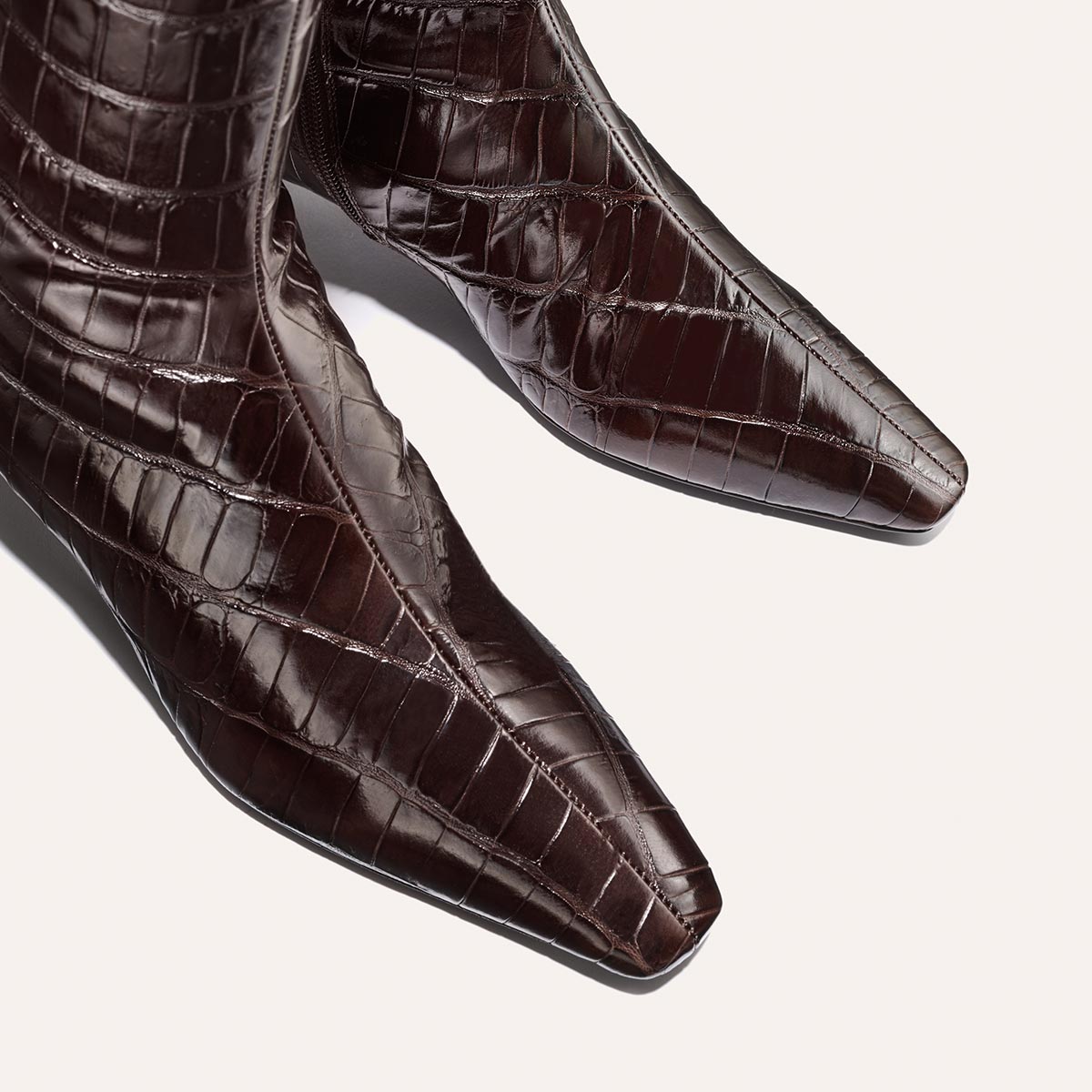 Close-up of Margaux’s The Imogen boots in espresso croc-embossed leather, featuring a pointed toe, set against a plain light background.