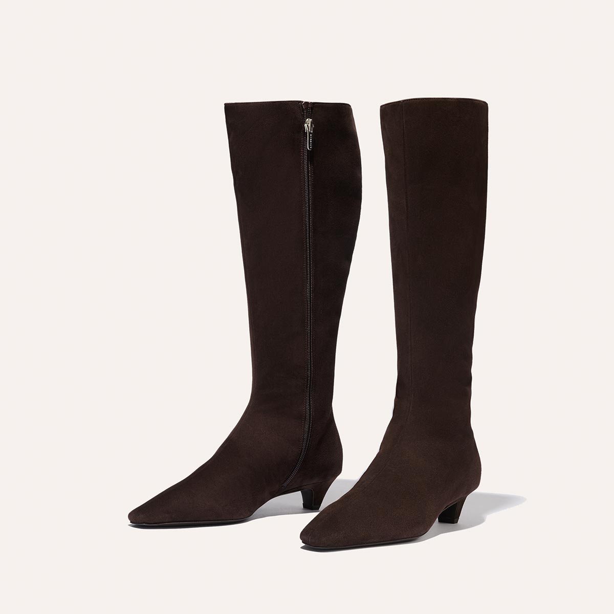 The Imogen - Espresso Suede by Margaux: dark brown knee-high suede boots with a low kitten heel, pointed toe, and side zipper, showcased on a plain light background.
