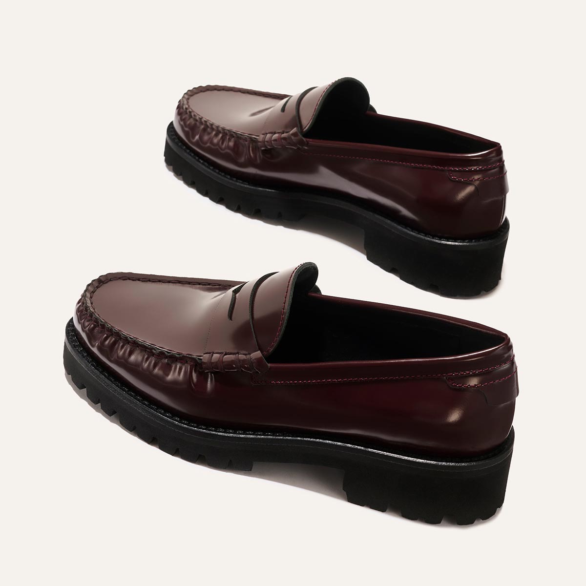 Margaux’s The Louisa Loafer in Burgundy Calf features glossy leather, black chunky lug soles, a classic penny slot, and visible toe stitching. Leather-lined for comfort, they’re showcased on a plain light background.