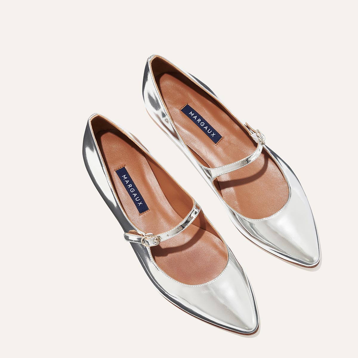The Mary Jane in shiny Silver Mirror Patent, a ballet flat with a pointed toe and an adjustable strap for a secure fit.