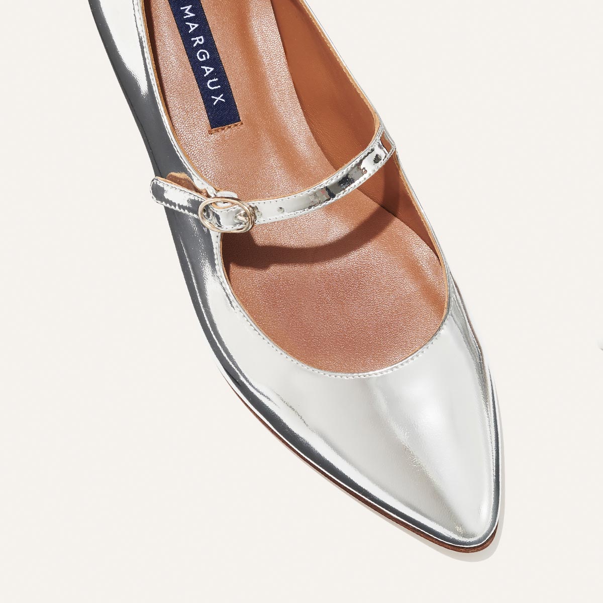 The Mary Jane in shiny Silver Mirror Patent, a ballet flat with a pointed toe and an adjustable strap for a secure fit.