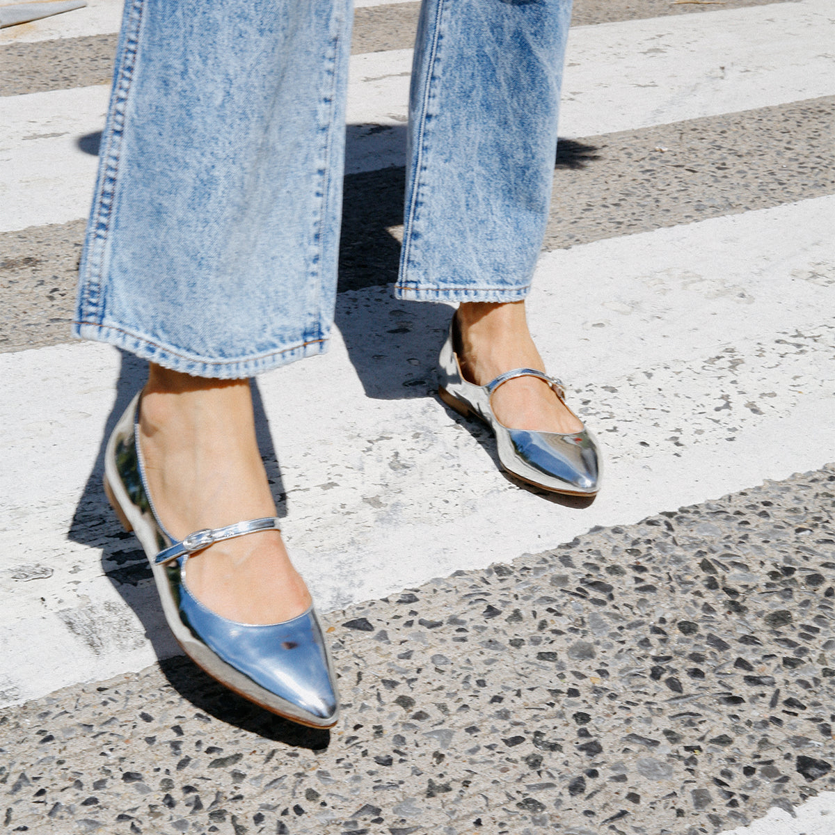The Mary Jane in shiny Silver Mirror Patent, a ballet flat with a pointed toe and an adjustable strap for a secure fit.