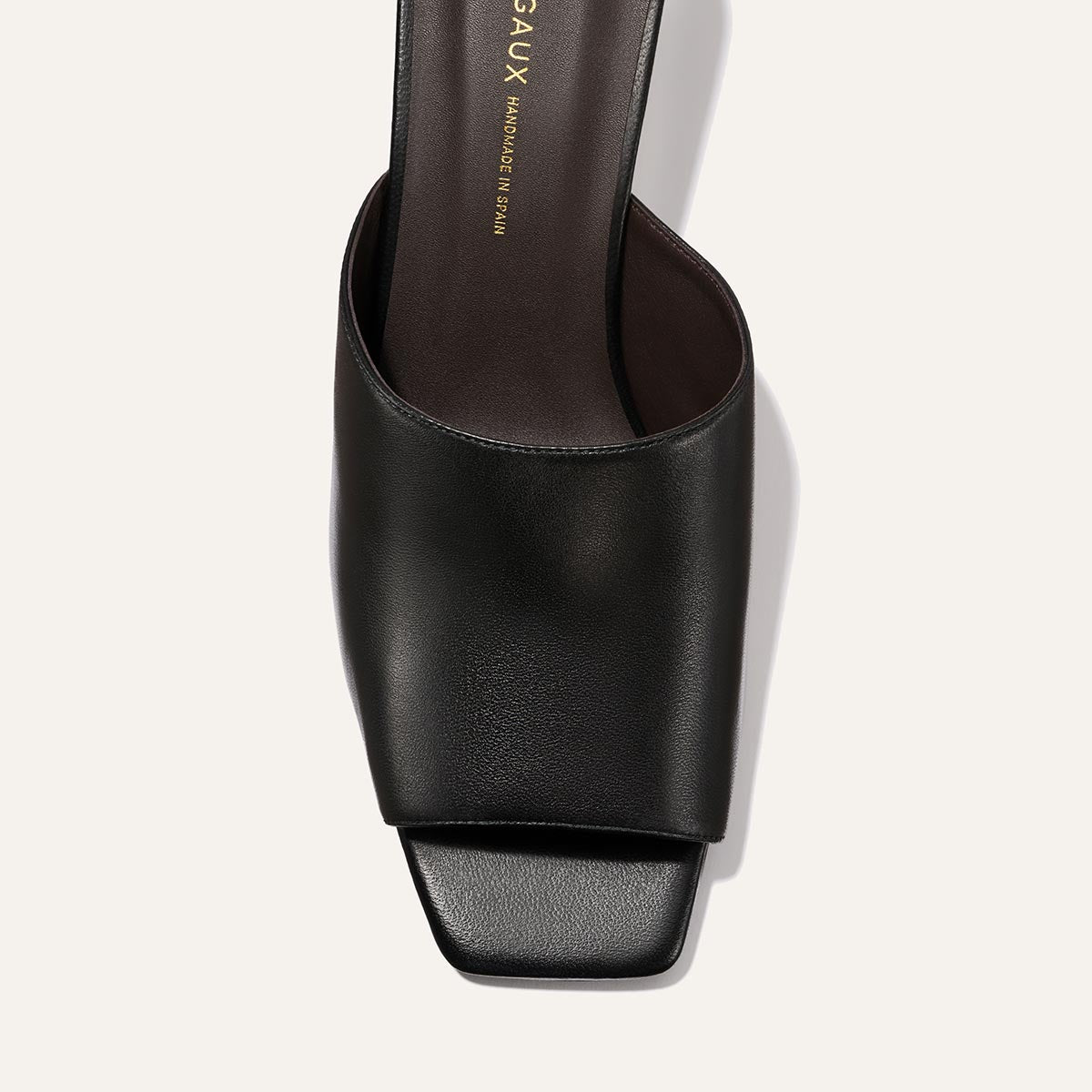 A close-up top view of Margaux's The Naomi 50 - Black Nappa sandal, showcasing an open square toe, wide soft leather upper, square block heel, and gold branding on the insole.