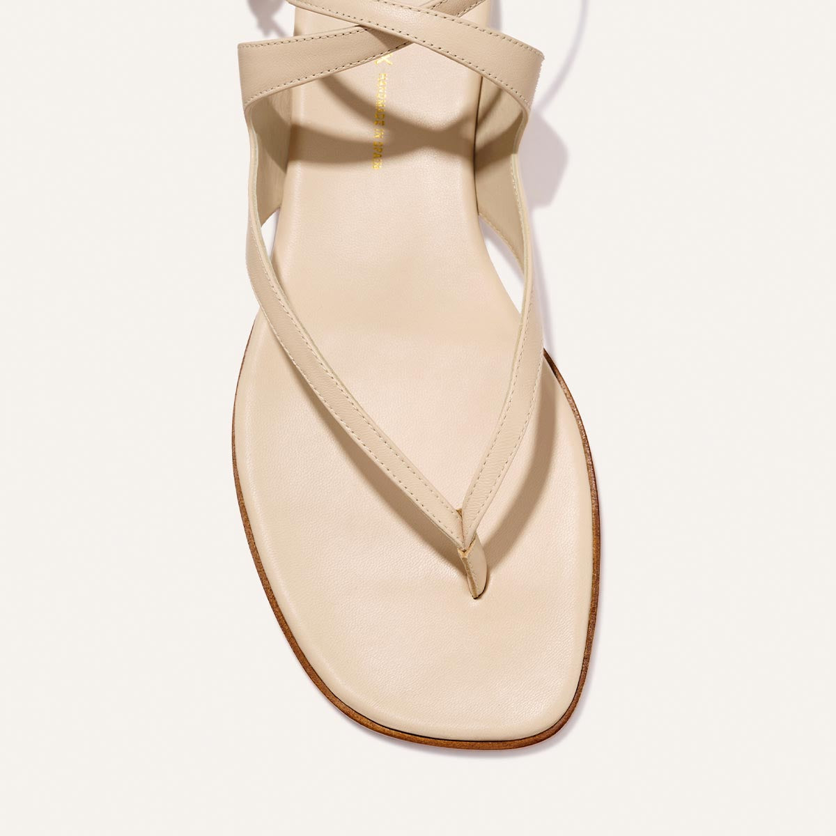 A close-up of Margaux’s The Palermo Sandal - Magnolia Nappa, showcasing its square toe, thin crisscross straps, and cushioned insole—ideal summer footwear—displayed against a white background.