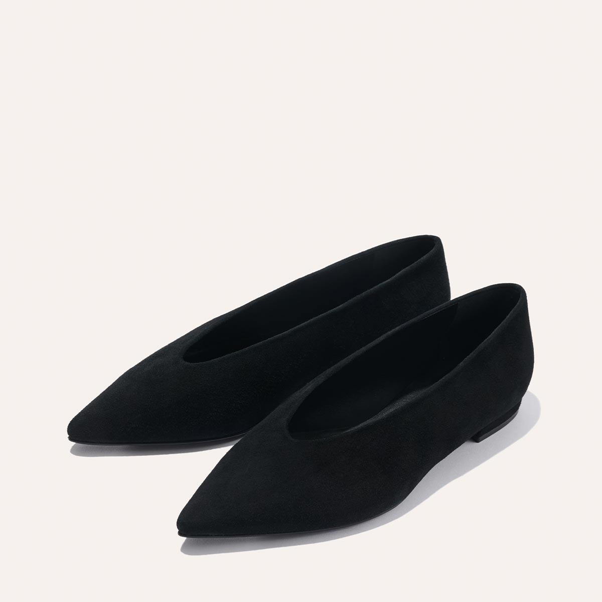 The Parra - Black Suede flats by margaux-development feature a pointed toe, structured silhouette, and luxurious suede-like material, showcased against a light neutral background.