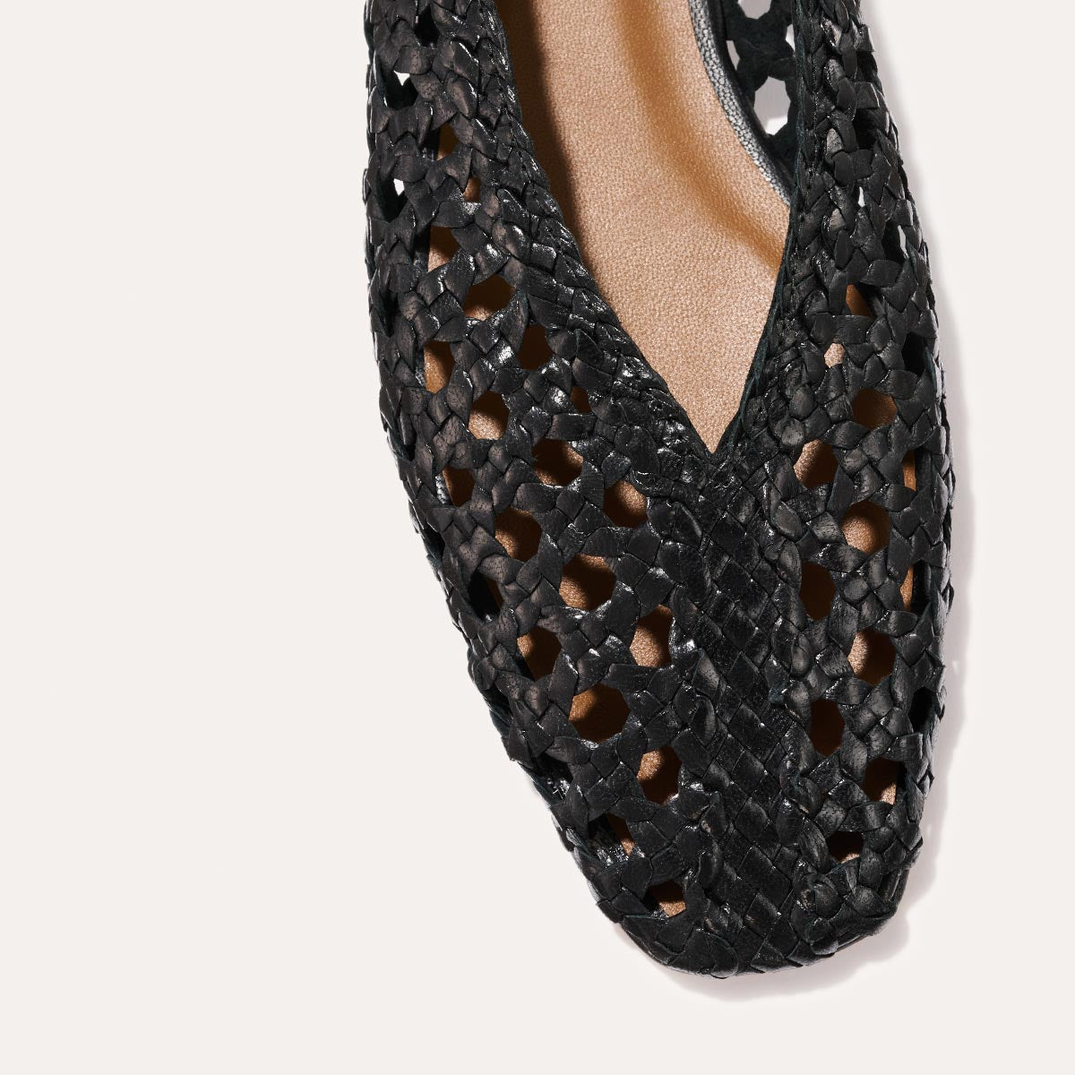Close-up of The Woven Paz SS25 - Black Leather by Margaux, featuring a pointed V-shaped cutout toe and black handwoven leather upper, revealing a tan insole underneath.