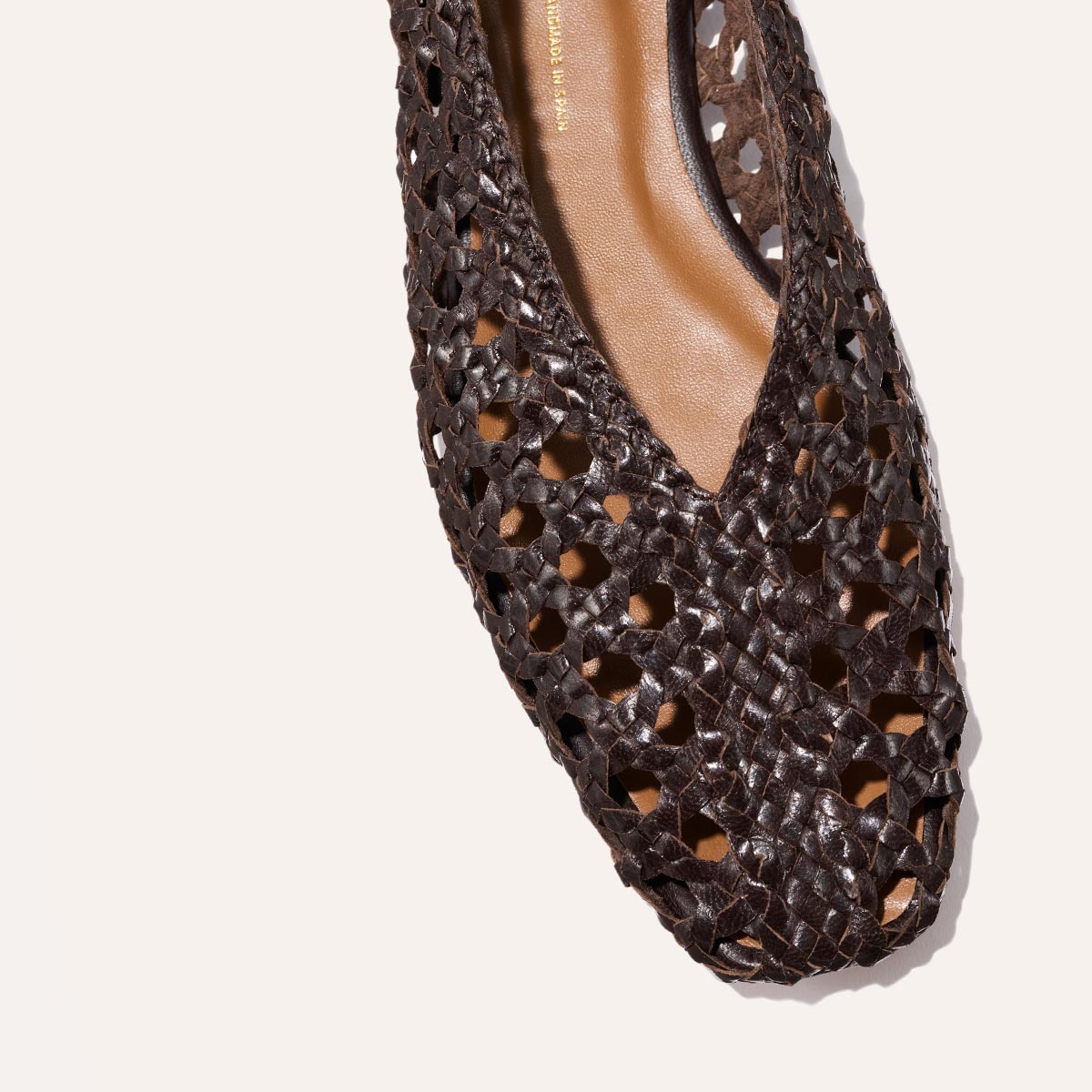 Close-up of The Woven Paz SS25 - Espresso Leather by Margaux, a handwoven flat shoe in dark brown leather with a pointed toe, geometric cutout pattern, higher rise, and partially visible tan insole.