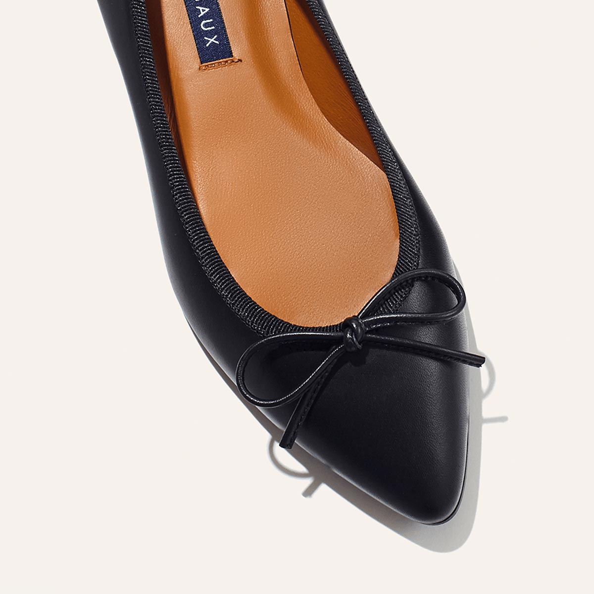 The Pointe in Black Nappa, a classic and comfortable ballet flat featuring a refined pointed toe design and decorative bow.