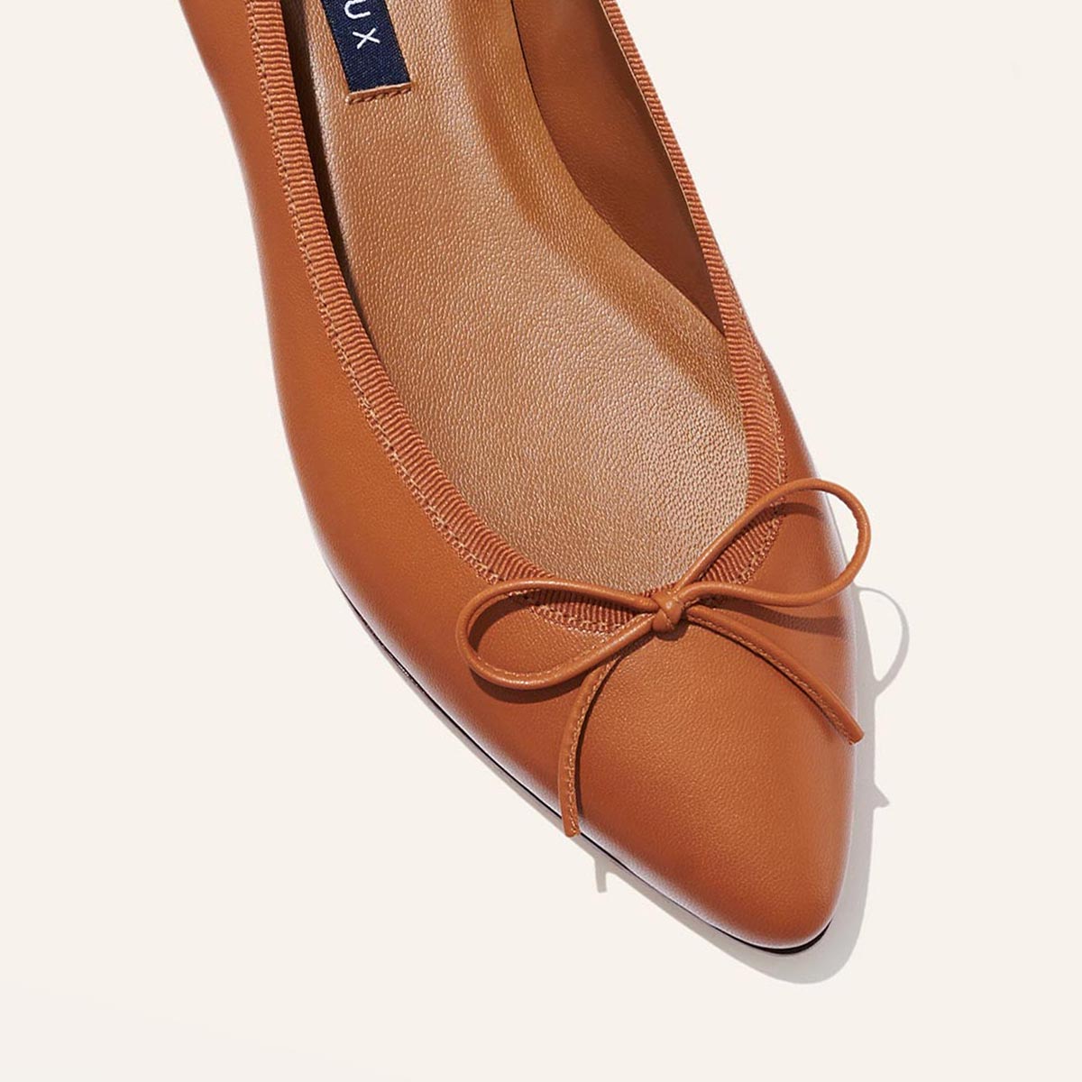 The Pointe in Saddle Nappa, a classic and comfortable ballet flat featuring a refined pointed toe design and decorative bow.