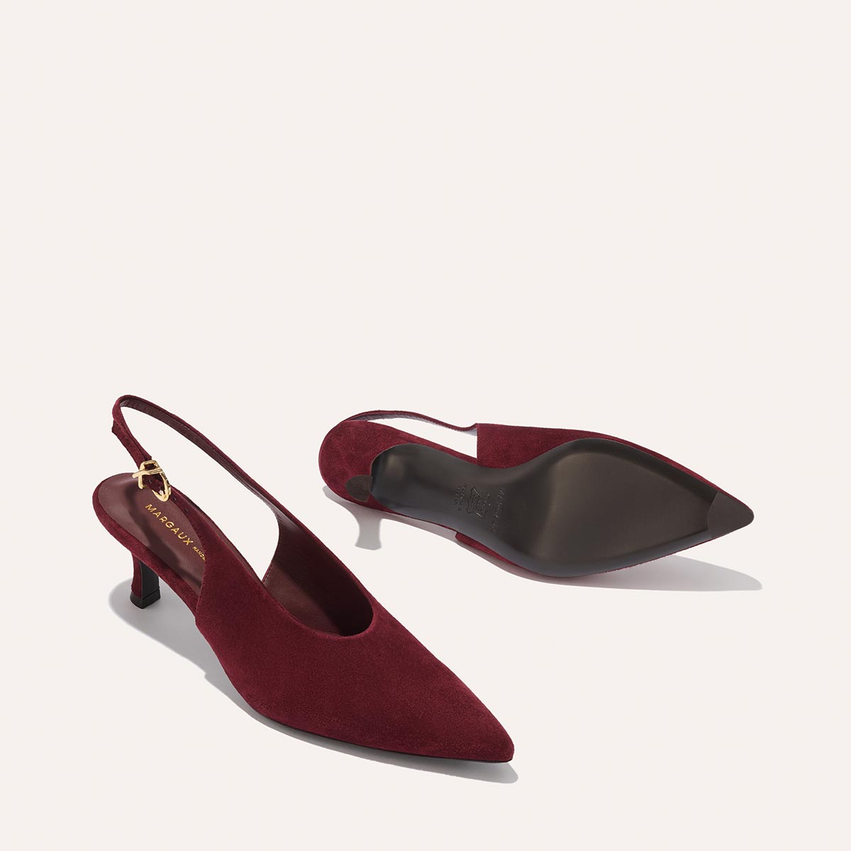 The Prado Sling - Burgundy Suede by margaux-development: a pair of burgundy suede slingback heels with pointed toes and low kitten heels, shown on a light background—one upright, the other on its side to display the sole.